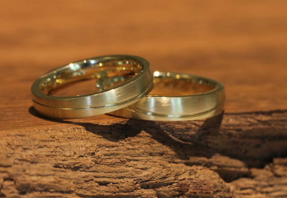 Imagen 029a: anillos de boda únicos realizados en oro amarillo con una línea curva desde el curso del anillo de bodas.