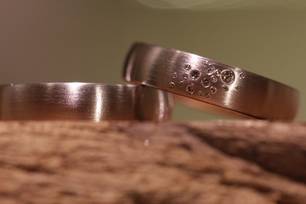 Immagine 195b: fedi nuziali monocolore in oro grigio, anello da donna con diversi diamanti di diverse dimensioni.