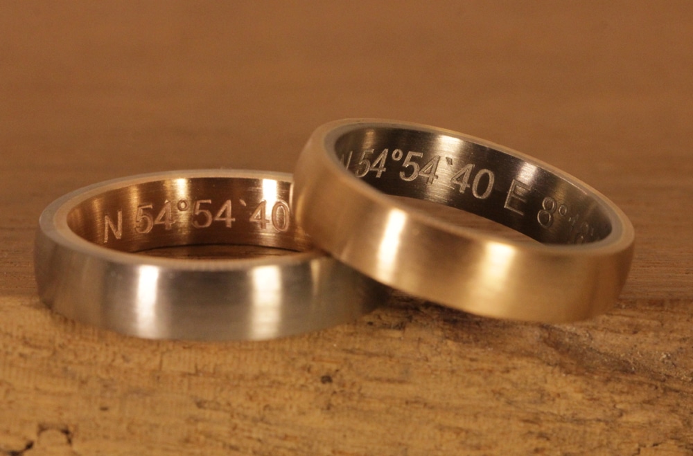 laser engraving of coordinates in block letters in two-tone wedding rings
