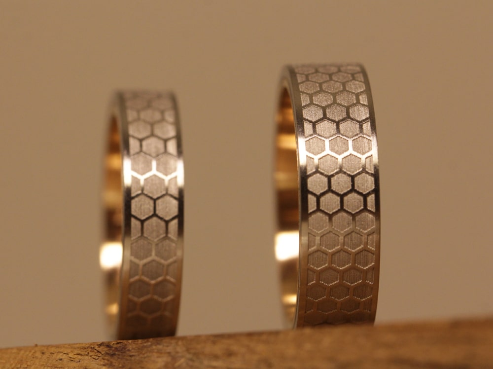 Wedding rings in platinum with rose gold and laser engraving outside honeycomb pattern inside lettering