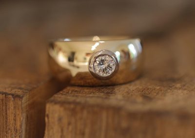 wide jewelry ring made of yellow gold with a brilliant in a white gold setting
