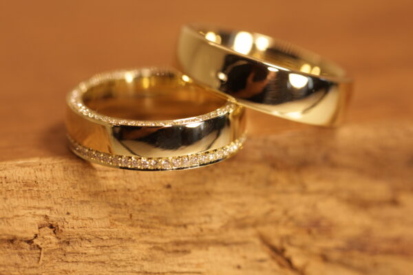 A pair of wedding rings polished in 750 yellow gold. Ladies ring decorated with white diamonds all around