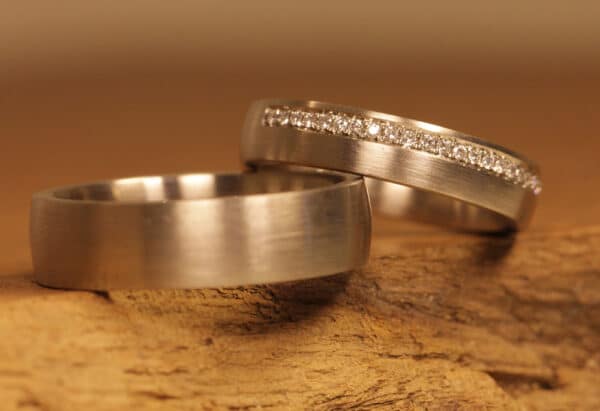 Un paio di fedi nuziali dal taglio opaco realizzate con anello da donna in oro grigio 750 con diamanti