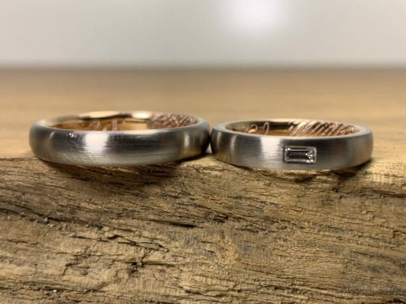 Un par de anillos de boda hechos de oro gris 585 y oro rosa, anillo de mujer con diamante baguette y grabado láser.