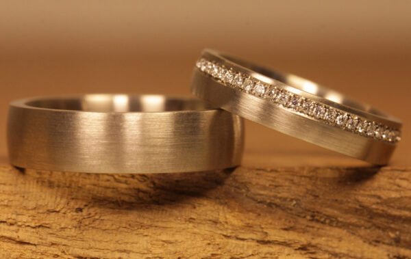 Un paio di fedi nuziali dal taglio opaco realizzate con anello da donna in oro grigio 750 con diamanti